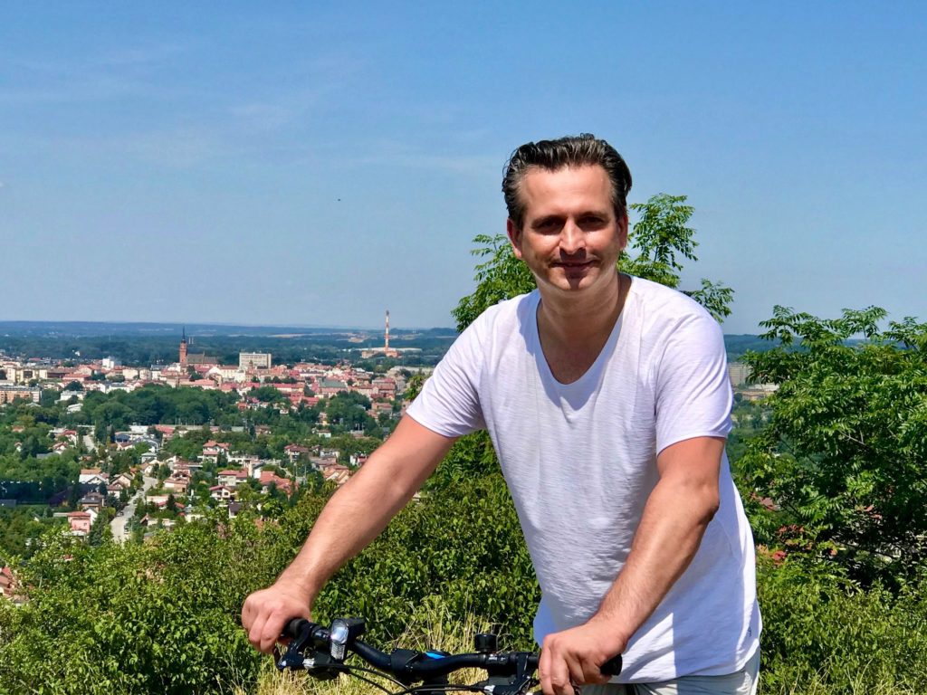 Robert Wardzała z rowerem na tle panoramy miasta