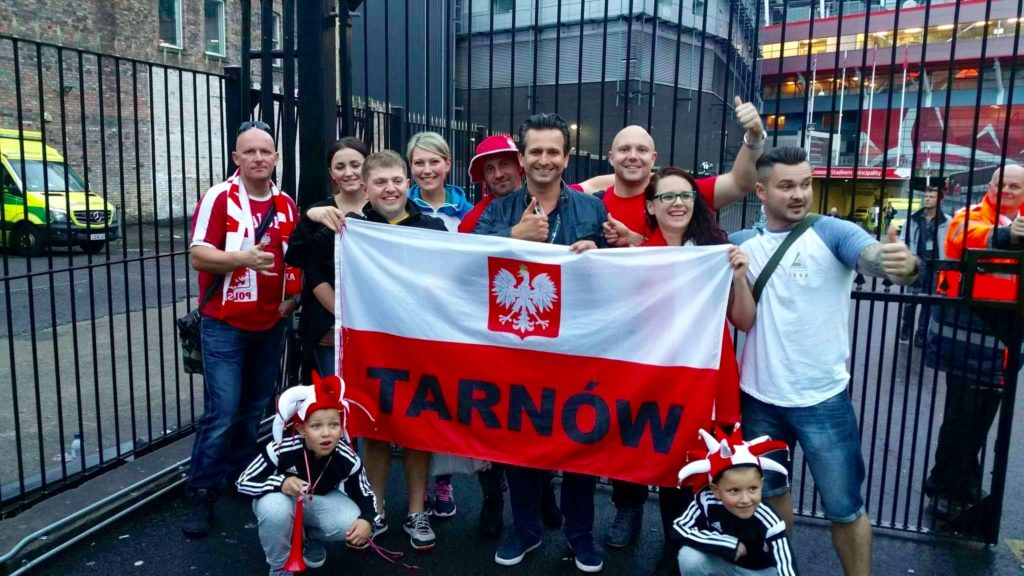 Grupa kibiców z biało-czerwoną flagą z napisem Tarnów