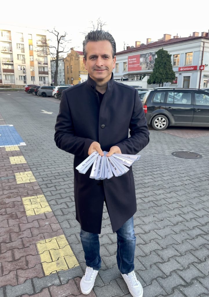Robert Wardzała na ulicy z materiałami w dłoniach