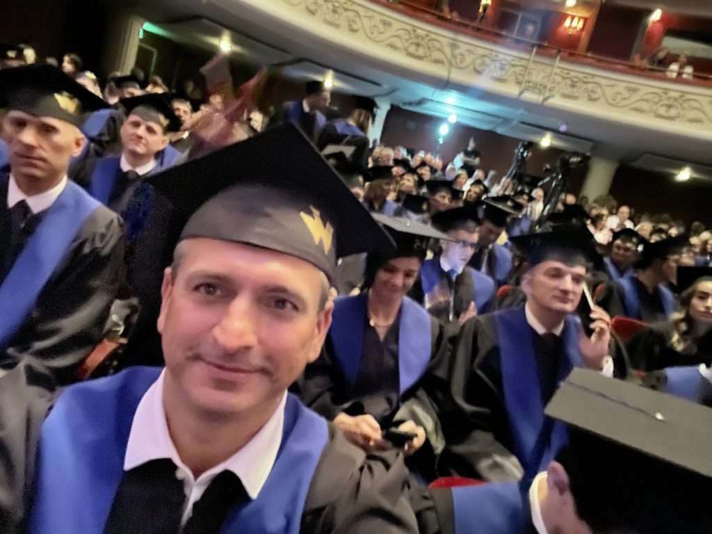 Robert Wardzała z absolwentem w birecie w sali uroczystości