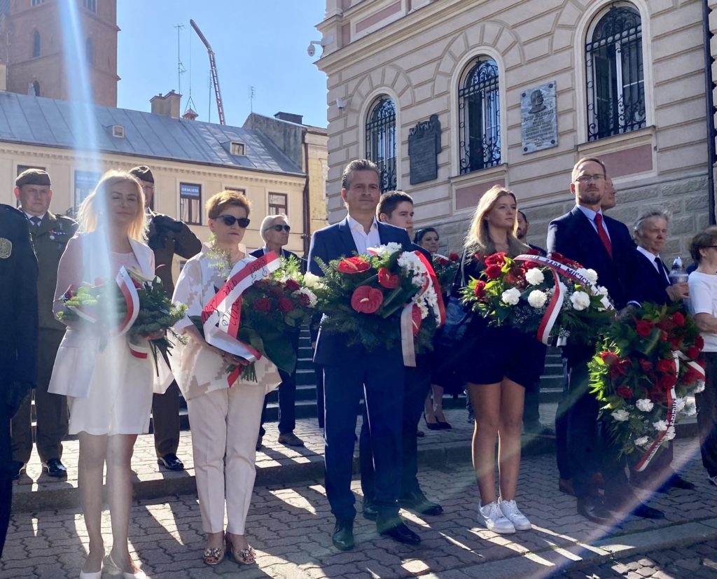 Grupa osób z wieńcami przed kościołem