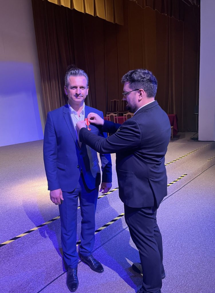 Robert Wardzała i mężczyzna na scenie podczas wręczania odznaczenia