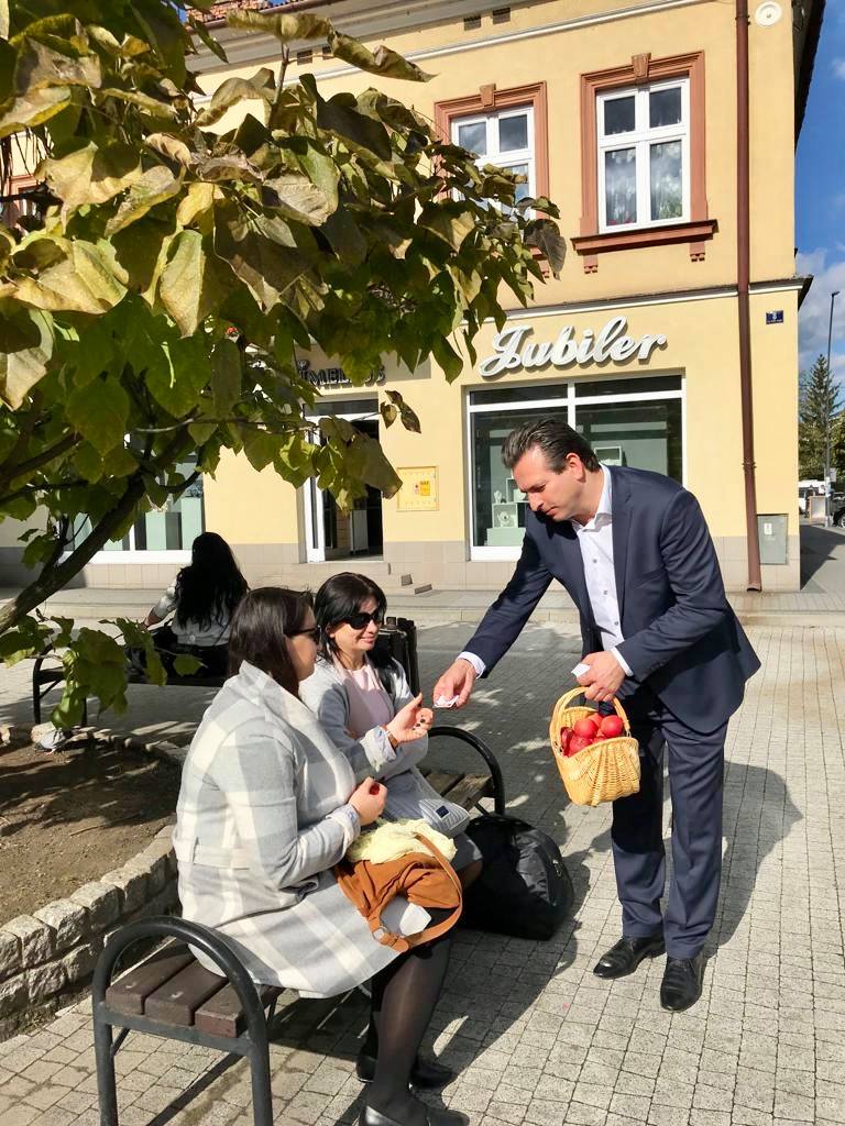 Robert Wardzała wręcza kwiaty osobie siedzącej na ławce
